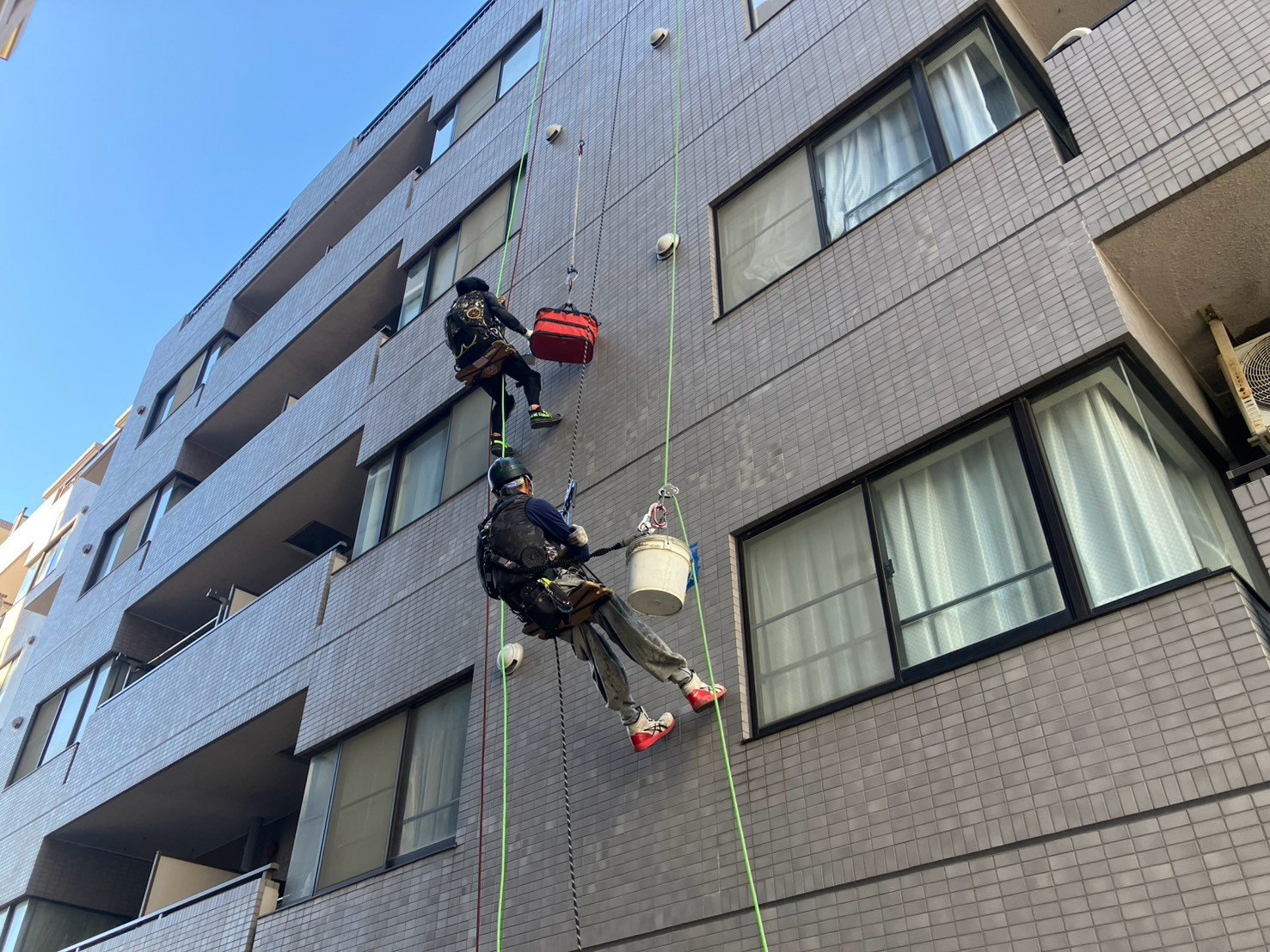 分譲マンション 換気ガラリ廻りシール工事 ブランコ(ロープアクセス)による作業の様子